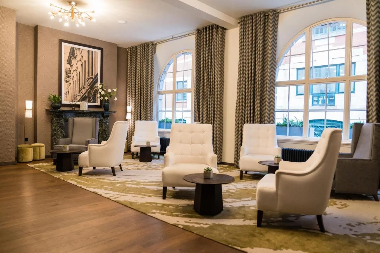 a waiting room with chairs and a table and windows at Stock Exchange Hotel, Manchester, Autograph Collection in Manchester